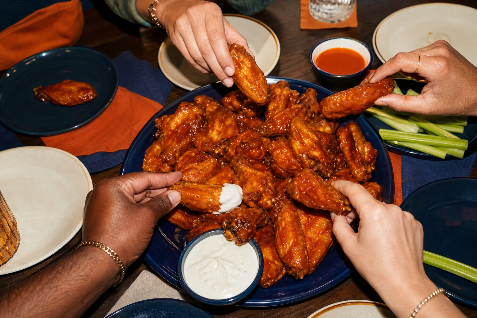 Sauced wings shared around a full table